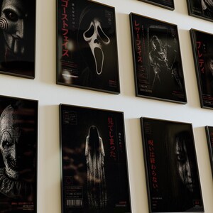 Puede incluir: Una colecci&oacute;n de carteles enmarcados de pel&iacute;culas de terror, cada uno con un personaje o escena diferente. Los carteles son predominantemente en blanco y negro con texto japon&eacute;s rojo. Los personajes incluyen una figura enmascarada, una cara de fantasma y una mujer con cabello negro largo.