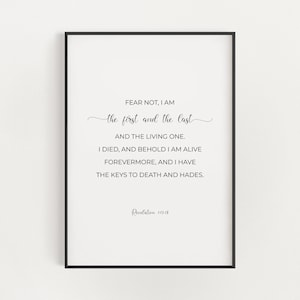 May include: A framed print with a white background and black text. The text reads "FEAR NOT, I AM the first and the last AND THE LIVING ONE. I DIED, AND BEHOLD I AM ALIVE FOREVERMORE, AND I HAVE THE KEYS TO DEATH AND HADES." Revelation 1:17-18 is at the bottom.