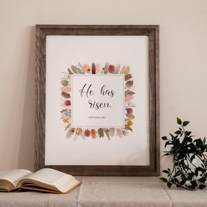 Ha resucitado arte de pared del versículo bíblico de Pascua imprimible con una corona de flores silvestres de acuarela boho, impresión digital de las Escrituras florales de Mateo 18:6