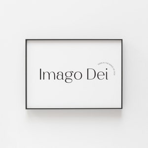 May include: Black framed print with the text "Imago Dei" in a simple font. The text is centered on the print and is surrounded by a white background. The print is framed in a black frame.