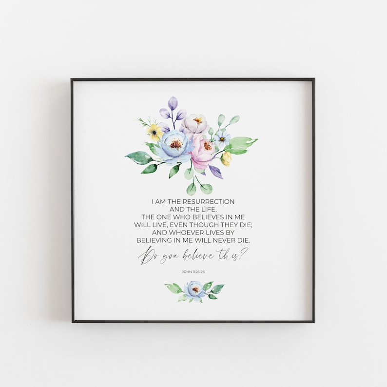 May include: Square framed print featuring a floral arrangement in pastel colors above a religious quote. The text reads "I AM THE RESURRECTION AND THE LIFE... Do you believe this?" in elegant script. The frame is black.
