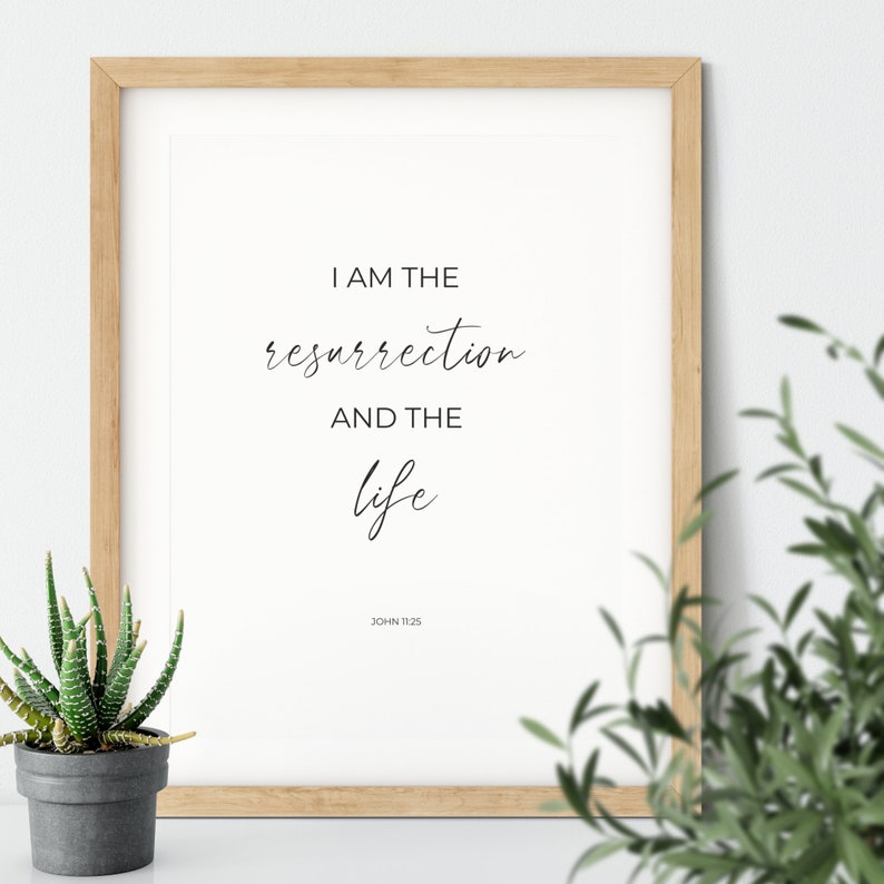 May include: A framed print with a white background and black text that reads "I am the resurrection and the life" with "John 11:25" below the text.