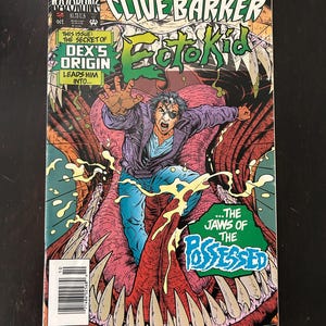 May include: A comic book cover featuring the title "Ectokid" with a man in a purple jacket and blue jeans, with an eye patch, reaching out. The cover has the text "The Jaws of the Possessed" and "Super Heroes From The Mind of Clive Barker".