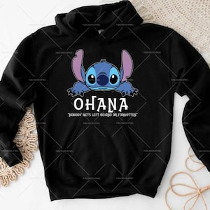 May include: Black hoodie with a blue cartoon character graphic and the word "OHANA" in white. The phrase "NOBODY GETS LEFT BEHIND OR FORGOTTEN" is printed below the word "OHANA" in white.
