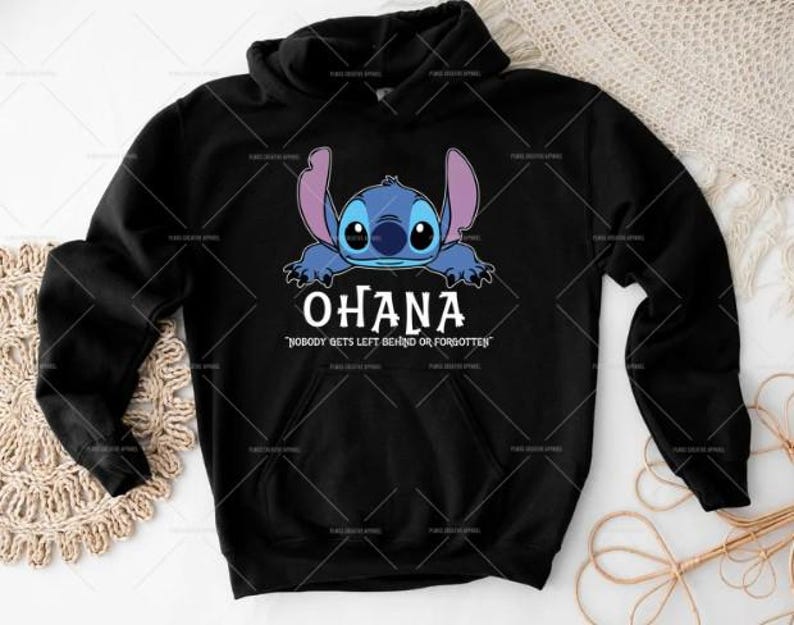 May include: Black hoodie with a blue cartoon character graphic and the word "OHANA" in white. The phrase "NOBODY GETS LEFT BEHIND OR FORGOTTEN" is printed below the word "OHANA" in white.