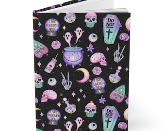 May include: A black journal with a spooky, pastel-colored pattern. The pattern includes ghosts, eyeballs, moons, cauldrons, and tombstones. The text on the tombstones reads "Do Not Enter" and the text on the crystal balls reads "I See Through You".