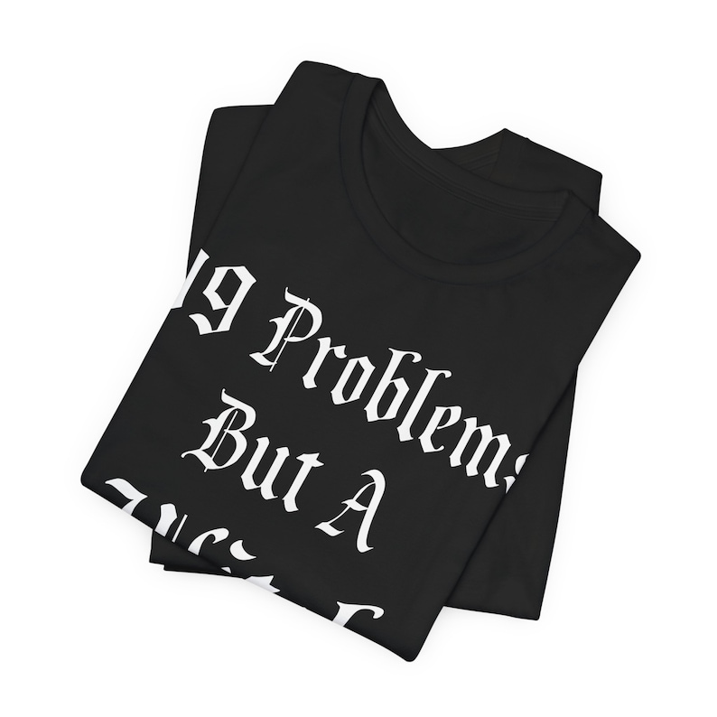 May include: Black t-shirt with white text that reads "No Problems But A Mess". The shirt is folded in half.
