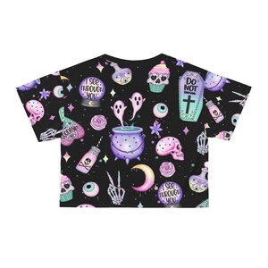 May include: Black crop top with a repeating pattern of spooky illustrations. The design includes skulls, potion bottles, ghosts, a cauldron, and the text "I see through you" and "Do not disturb".