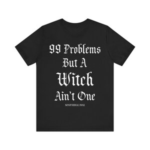 May include: Black t-shirt with white text that reads "99 Problems But A Witch Ain't One" and the words "Nocturnal Nood" in smaller font below.