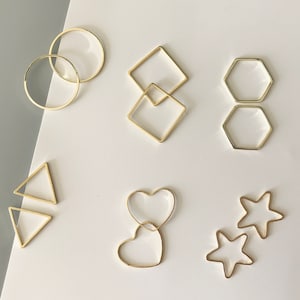 Può includere: Un set di elementi per orecchini dorati in varie forme, tra cui cerchi, quadrati, esagoni, triangoli, cuori e stelle.