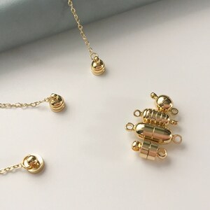 May include: Gold magnetic clasps for jewelry making. The clasps are made of metal and have a round shape. They are designed to be used with necklaces, bracelets, and other jewelry.