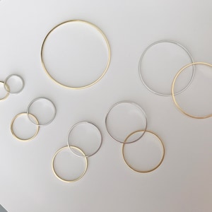 May include: A collection of gold and silver rings of varying sizes. The rings are arranged on a white surface.