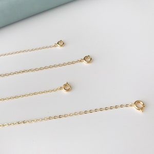 May include: Three gold chain extenders of different lengths. The chains are made of small, linked circles.