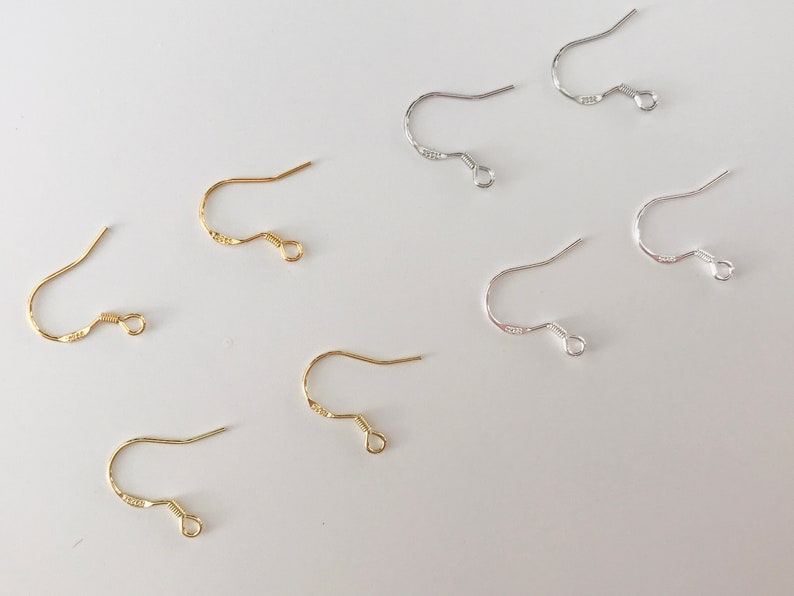 May include: A set of gold and silver earring hooks. The hooks are made of metal and have a simple design. They are perfect for making your own earrings.