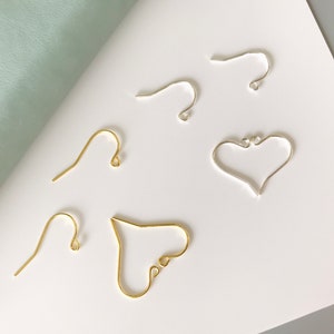 Op de afbeelding: Vijf oorbel bevindingen, twee goud en drie zilver. De gouden bevindingen zijn een haak en een hartvorm. De zilveren bevindingen zijn een haak en twee hartvormen.