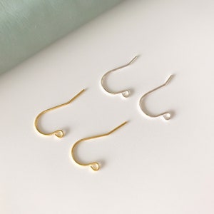 Op de afbeelding: Twee paar oorhaken, &eacute;&eacute;n paar is goud en het andere is zilver.