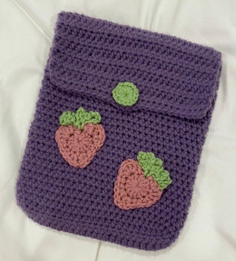 May include: Purple crocheted pouch with a flap closure and two pink and green strawberry appliques.