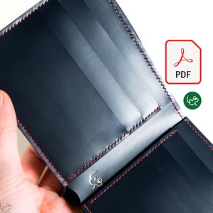 May include: A black leather wallet with red stitching and a gold logo. The wallet is open to reveal multiple card slots and a billfold.