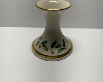 May include: White ceramic candle holder with a gold rim and a design of green holly leaves and red berries.