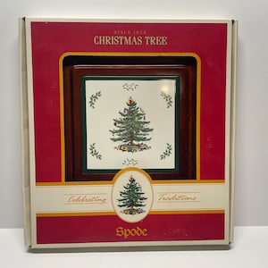 May include: A white box with a red border and a wooden frame with a white ceramic tile inside. The tile features a green Christmas tree with red and gold ornaments. The box says "Since 1938 Christmas Tree" and "Celebrating Traditions" with the word "Spode" at the bottom.