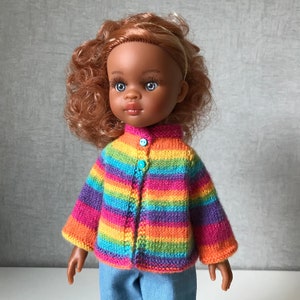 K&ouml;nnte beinhalten: Puppe mit brauner Haut, blauen Augen und roten Locken, die einen gestreiften Strickcardigan in Regenbogenfarben mit blauen Kn&ouml;pfen und Jeans tr&auml;gt. Der Cardigan hat Streifen in Pink, Orange, Gelb, Gr&uuml;n und Lila.