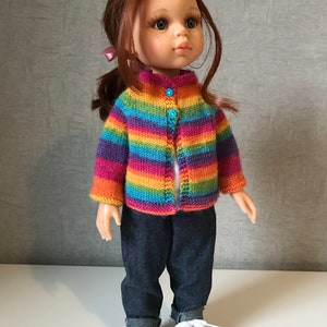 K&ouml;nnte beinhalten: Eine Puppe mit einem gestreiften Strick-Cardigan in Regenbogenfarben mit blauen Kn&ouml;pfen, dunkelblauen Jeans und schwarz-wei&szlig;en Turnschuhen. Die Puppe hat rotes Haar und einen Pferdeschwanz.