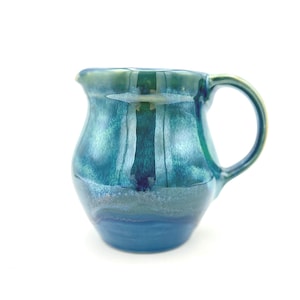 Jarra de cerámica, de tamaño mediano, con esmaltes verdes y azules.