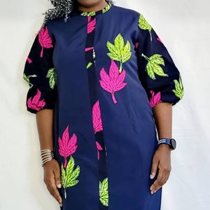 May include: A navy blue dress with a button-up front and a leaf print in pink and green. The dress has a slightly flared skirt and three-quarter sleeves.