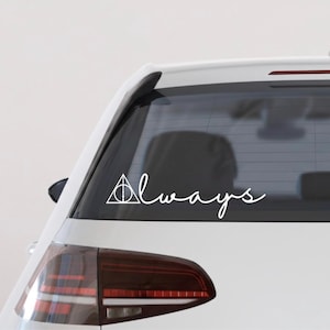 May include: White vinyl decal applied to a car's rear window. The decal features the word "Always" in a cursive font, accompanied by a Deathly Hallows symbol. The car is white, with a dark tinted window.