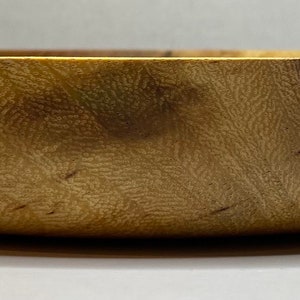 Puede incluir: Un cuenco de madera con un acabado natural de vetas. El cuenco tiene una forma redondeada y una superficie lisa y pulida. El color es un marr&oacute;n claro c&aacute;lido con vetas marrones m&aacute;s oscuras. El cuenco est&aacute; vac&iacute;o y parece nuevo.