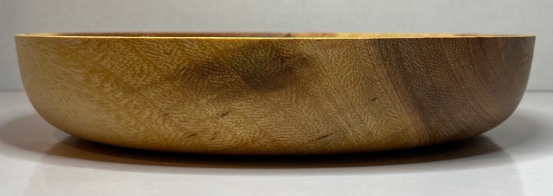 Puede incluir: Un cuenco de madera con un acabado natural de vetas. El cuenco tiene una forma redondeada y una superficie lisa y pulida. El color es un marr&oacute;n claro c&aacute;lido con vetas marrones m&aacute;s oscuras. El cuenco est&aacute; vac&iacute;o y parece nuevo.