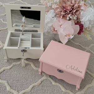 May include: Two wooden jewellery boxes. One is white with a mirrored lid and a ballerina figurine inside. The other is pink with the name "Adeline" on the lid. Both have a lock and key.