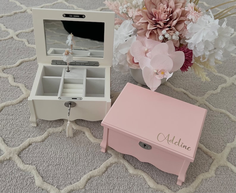 May include: Two wooden jewellery boxes. One is white with a mirrored lid and a ballerina figurine inside. The other is pink with the name "Adeline" on the lid. Both have a lock and key.