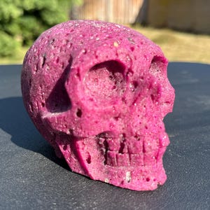 May include: A pink skull made of a textured material. The skull is detailed with a textured surface and a defined jawline.