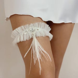 Elegant light ivory wedding garter with white ostrich feather fringe charm, Victorian tulle garter for bride, Whimsical bling bridal garter