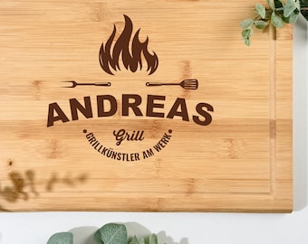 Pode incluir: Tábua de corte retangular de bambu com uma ranhura ao redor da borda. A tábua apresenta o nome "ANDREAS" com um gráfico de chama e as palavras "Grill" e "Grillkünstler am Werk" em marrom.