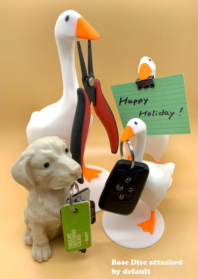 May include: A white goose figurine holding a pair of red pliers, a smaller white goose figurine holding a green note with the text "Happy Holiday!" and a white dog figurine holding a set of keys and a green card with the text "SMART SAVINGS CARD H MART".