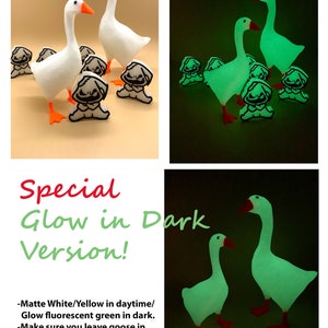 May include: Two white goose figurines with black eyes and orange beaks. The geese are standing on a light brown surface. The geese glow green in the dark. The text "Special Glow in Dark Version!" is written in red and black letters. The text below the title reads: "Matte White/Yellow in daytime/ Glow fluorescent green in dark. -Make sure you leave goose in bright light room/under light so it can absorb &shine. - Avoid outdoor direct sunlight."