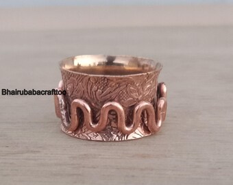 May include: A copper ring with a textured, floral design and a wavy, textured band.
