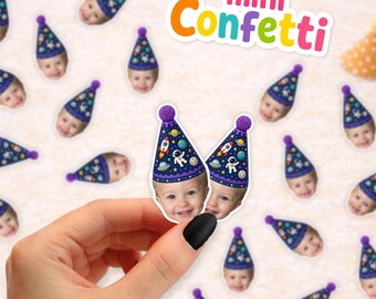 May include: Custom confetti pieces featuring a child's face wearing a dark blue party hat with a space-themed print of rockets, planets, and stars. The text "mini Confetti" is displayed in colorful letters at the top of the image.