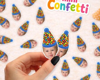 May include: A collection of small paper confetti pieces featuring a baby's face wearing a blue party hat covered in colorful candy-like spheres. The text 'mini Confetti' appears in the upper right corner in a multi-colored, rounded font.