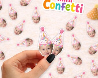 May include: Custom party confetti featuring small die-cut images of a child's face wearing a pink unicorn party hat with a pom-pom top. The text mini Confetti is visible in the upper right corner, alongside two small yellow and blue party hats.