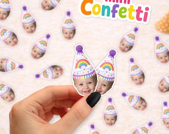 May include: Small paper confetti pieces featuring a printed photograph of a child wearing a white party hat with a rainbow and cloud design. The confetti is scattered across a surface, and the text mini Confetti is visible at the top.