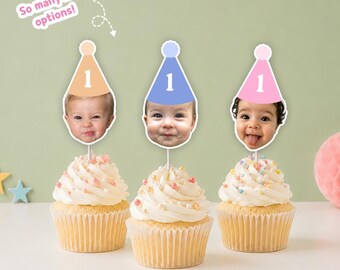 May include: Three cupcakes topped with custom photo toppers featuring infants wearing party hats with the number 1. The toppers come in peach, blue, and pink. Text on the image reads: So many hat options! The cupcakes have white frosting and sprinkles.