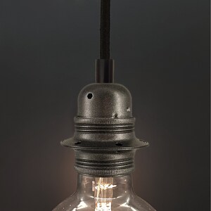 Peut inclure: Une douille de lampe en métal noir avec un cordon noir suspendu. La douille a une finition texturée et est conçue pour tenir une ampoule.