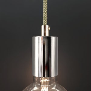 Op de afbeelding: Een close-up van een chromen lampfitting met een groen gevlochten snoer. De fitting is ontworpen om een standaard gloeilamp te houden.