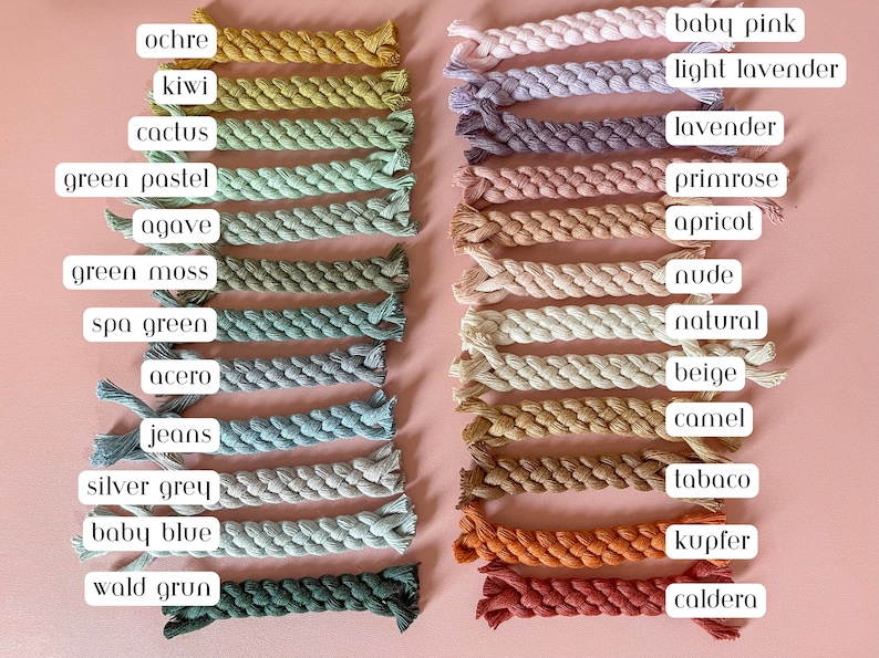 May include: A collection of twenty-two braided cotton cords arranged in two vertical columns. Each cord is labelled with colour names including ochre, kiwi, cactus, green pastel, agave, green moss, spa green, acero, jeans, silver grey, baby blue, wald grun, baby pink, light lavender, lavender, primrose, apricot, nude, natural, beige, camel, tabaco, kupfer, and caldera.