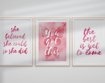 Könnte beinhalten: Drei gerahmte Drucke mit inspirierenden Zitaten in rosa und goldenen Buchstaben auf weißem Hintergrund. Der erste Druck sagt "Sie glaubte, dass sie es schaffen könnte, also tat sie es". Der zweite Druck zeigt einen Schmetterling mit den Worten "Du schaffst das". Der dritte Druck sagt "Das Beste kommt noch".