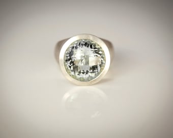 May include: A silver ring with a large, clear, faceted gemstone.