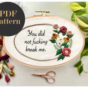 May include: Embroidered hoop art with the text "You did not fucking break me." surrounded by a floral design with red, pink, yellow, and white flowers and green leaves.